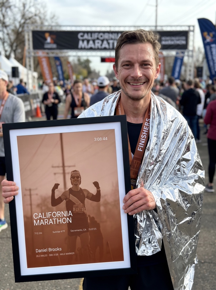 Marathon finisher with foil blanket holding his print