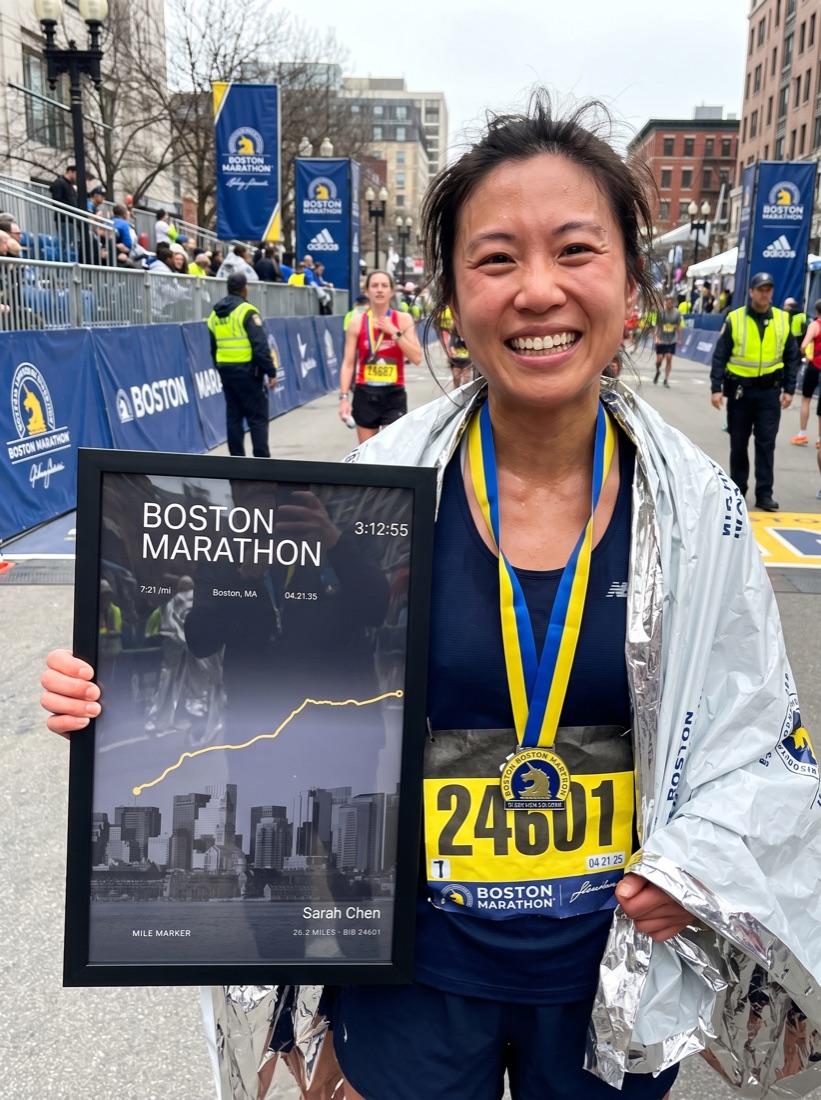 Runner holding her finisher print at the finish line